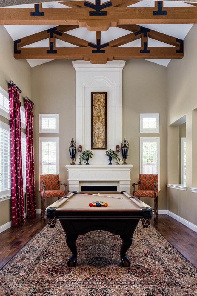 Photo of a large traditional enclosed games room in San Francisco with beige walls, dark hardwood flooring, a standard fireplace, a stone fireplace surround, no tv, a game room and brown floors.