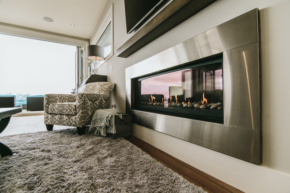 Medium sized traditional open plan games room in Vancouver with grey walls, light hardwood flooring, a standard fireplace, a metal fireplace surround and a built-in media unit.