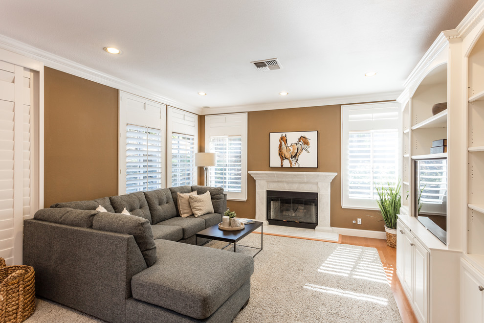 Imagen de sala de estar cerrada tradicional renovada con paredes marrones, suelo de madera en tonos medios, todas las chimeneas, pared multimedia y suelo marrón