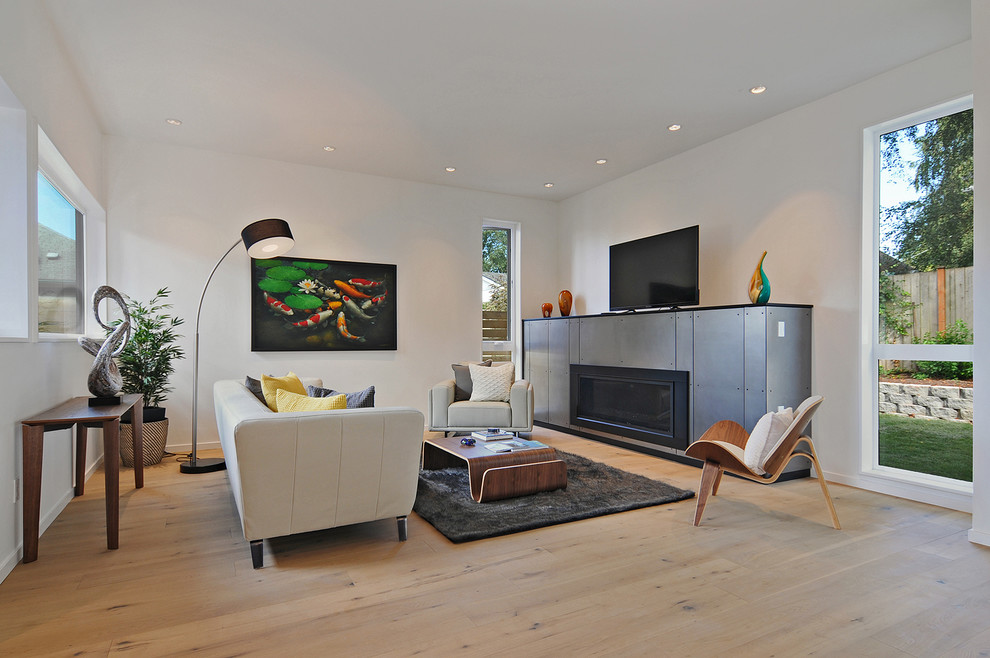 Ejemplo de sala de estar abierta retro de tamaño medio con paredes blancas, marco de chimenea de metal, televisor independiente, suelo de madera clara y chimenea lineal