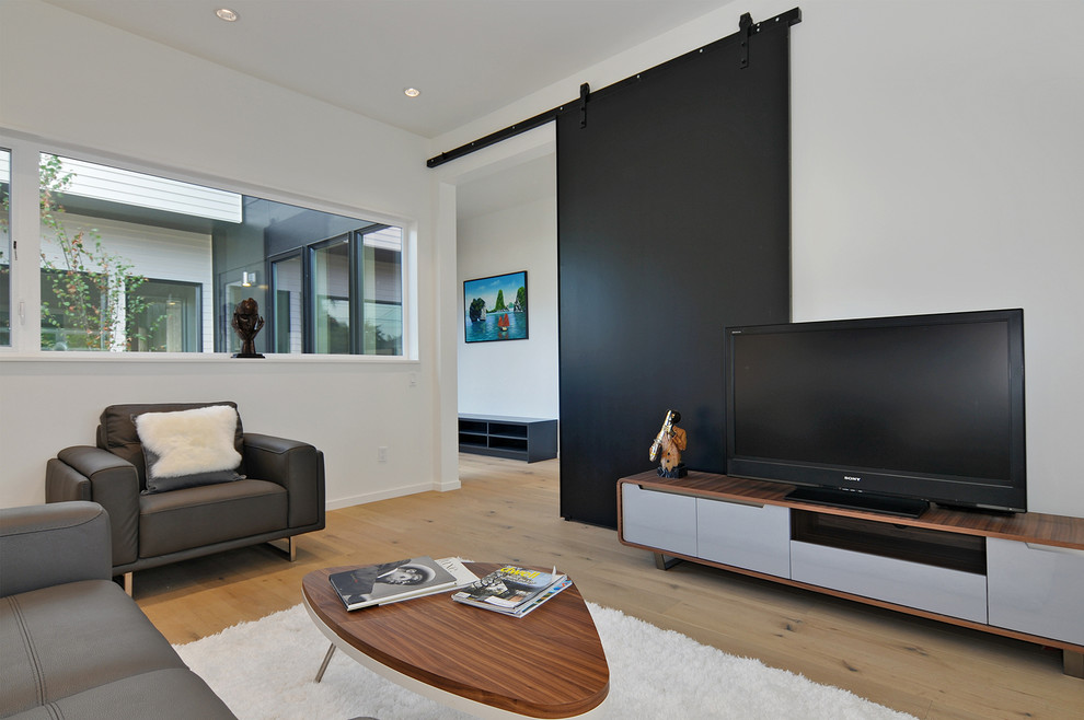 Immagine di un soggiorno minimalista di medie dimensioni e chiuso con libreria, pareti bianche, pavimento in legno massello medio e TV autoportante