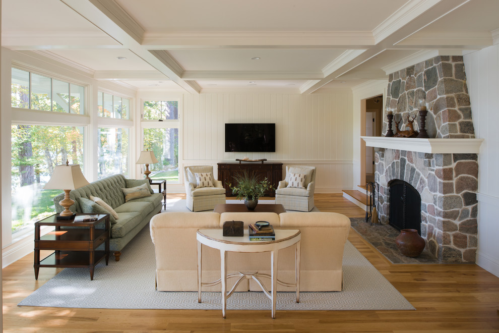 Elegant enclosed medium tone wood floor family room photo in Minneapolis with white walls, a standard fireplace, a stone fireplace and a wall-mounted tv