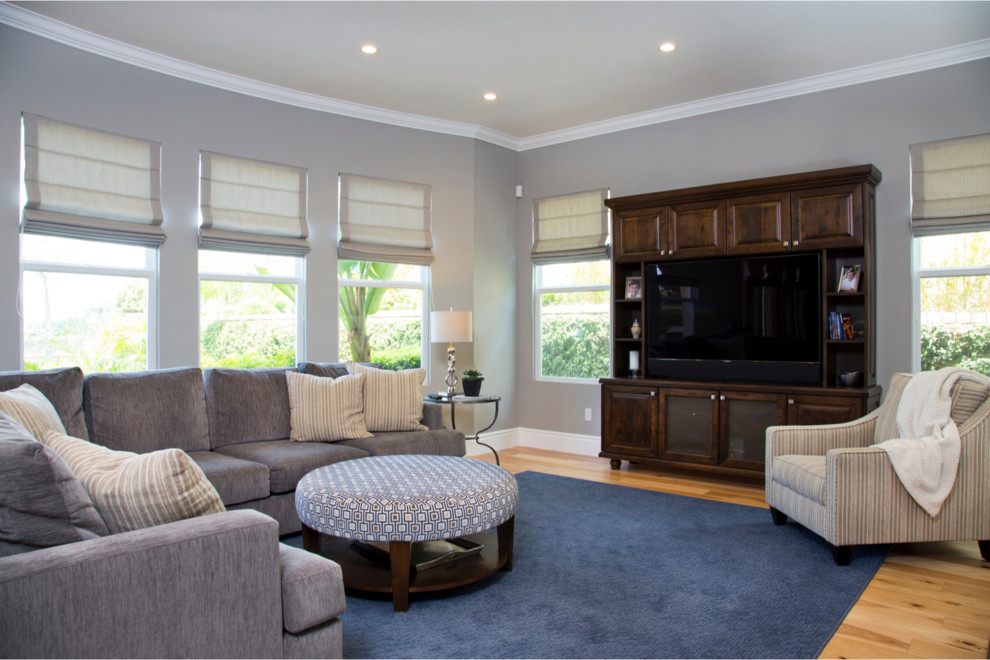 Mittelgroßes, Offenes Klassisches Wohnzimmer mit grauer Wandfarbe, hellem Holzboden, Multimediawand, Tunnelkamin und Kaminumrandung aus Stein in San Diego