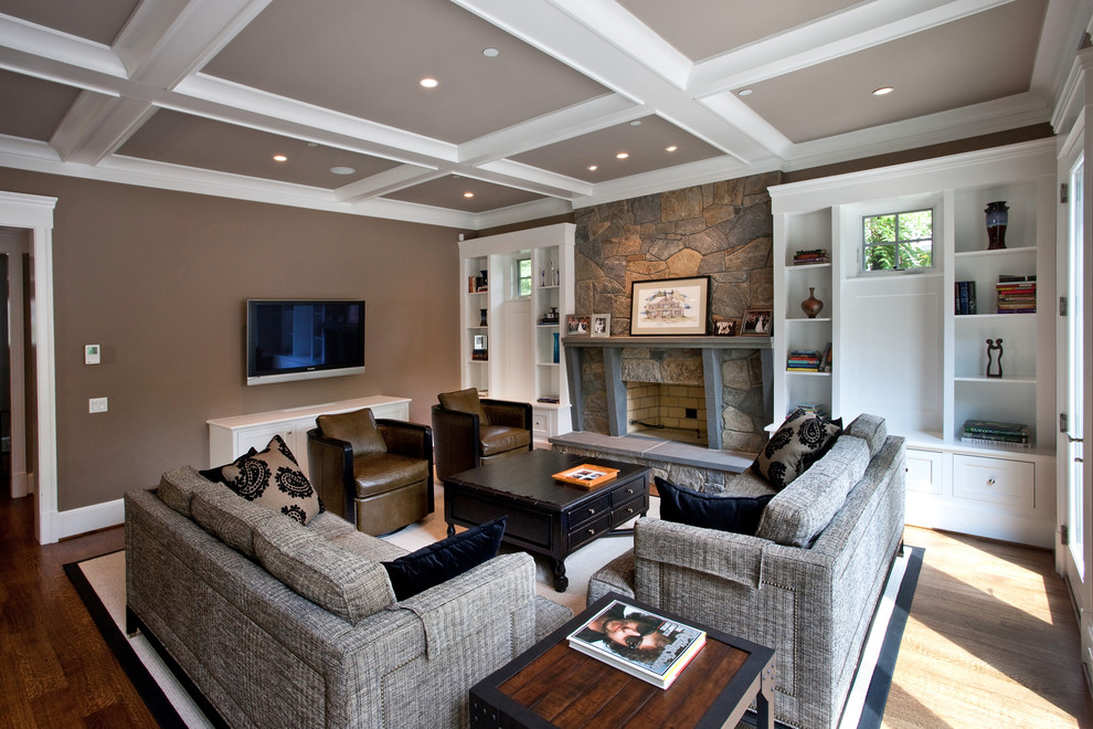 На фото: открытая гостиная комната в классическом стиле с коричневыми стенами, темным паркетным полом, стандартным камином, фасадом камина из камня и телевизором на стене