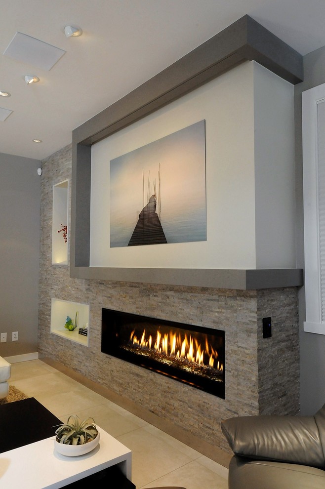 Cette image montre une salle de séjour design de taille moyenne avec un mur gris, un sol en carrelage de céramique, une cheminée ribbon, un manteau de cheminée en pierre, un téléviseur dissimulé et un sol blanc.