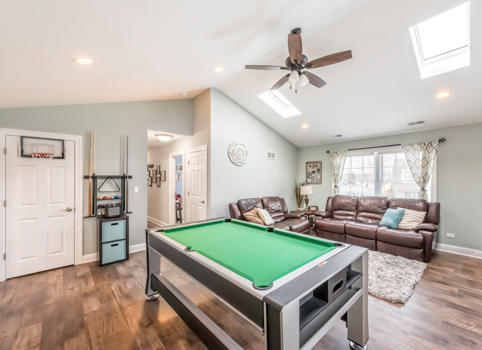 Game room - large traditional laminate floor, brown floor and vaulted ceiling game room idea in Chicago with gray walls and a tv stand