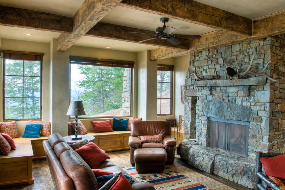 Foto de sala de estar cerrada rural grande sin televisor con suelo de madera en tonos medios, todas las chimeneas, marco de chimenea de piedra y paredes beige