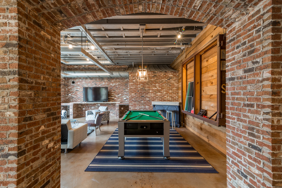 Cette image montre une salle de séjour urbaine ouverte avec salle de jeu, un mur rouge, sol en béton ciré et un sol gris.