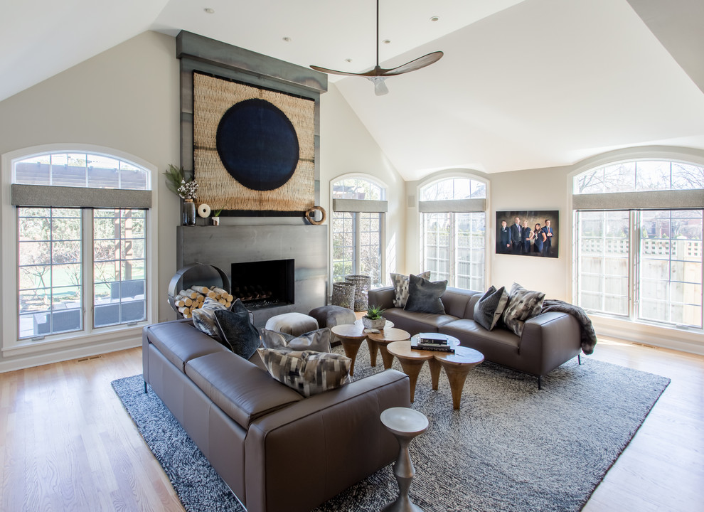 Idée de décoration pour une salle de séjour minimaliste de taille moyenne avec un sol en bois brun, une cheminée standard, un manteau de cheminée en métal et un téléviseur fixé au mur.
