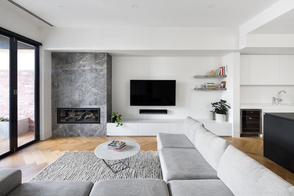 Идея дизайна: открытая гостиная комната среднего размера в современном стиле с коричневыми стенами, светлым паркетным полом, угловым камином, фасадом камина из камня, телевизором на стене, коричневым полом и ковром на полу