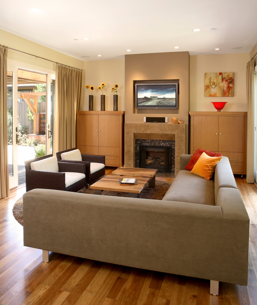 Inspiration for a medium sized contemporary open plan games room in San Francisco with beige walls, a standard fireplace, a tiled fireplace surround, a wall mounted tv and light hardwood flooring.