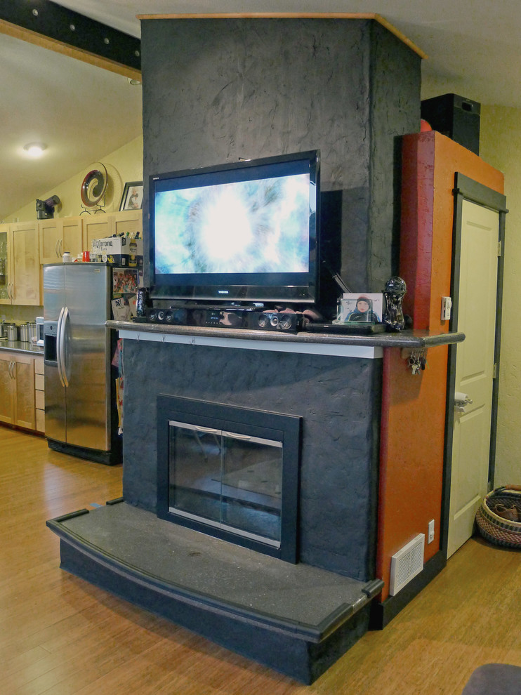 На фото: открытая гостиная комната среднего размера в современном стиле с разноцветными стенами, полом из бамбука, стандартным камином, фасадом камина из бетона, телевизором на стене и коричневым полом