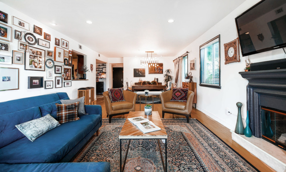 Stilmix Wohnzimmer mit weißer Wandfarbe, braunem Holzboden, Kamin, TV-Wand und braunem Boden in Los Angeles