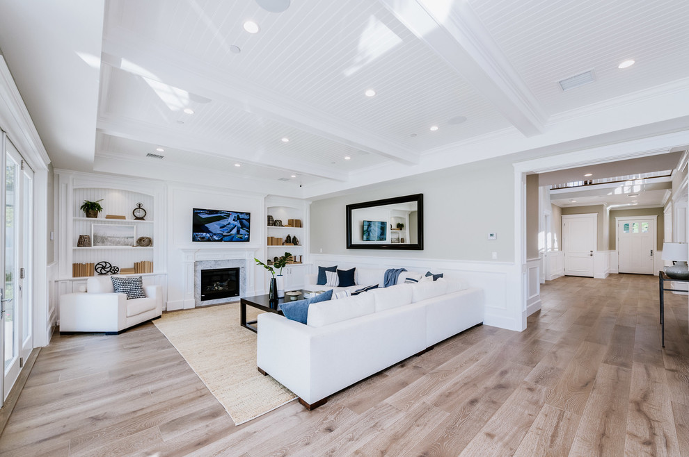 This is an example of a large traditional open plan games room in Los Angeles with a reading nook, beige walls, light hardwood flooring, a standard fireplace and a wall mounted tv.