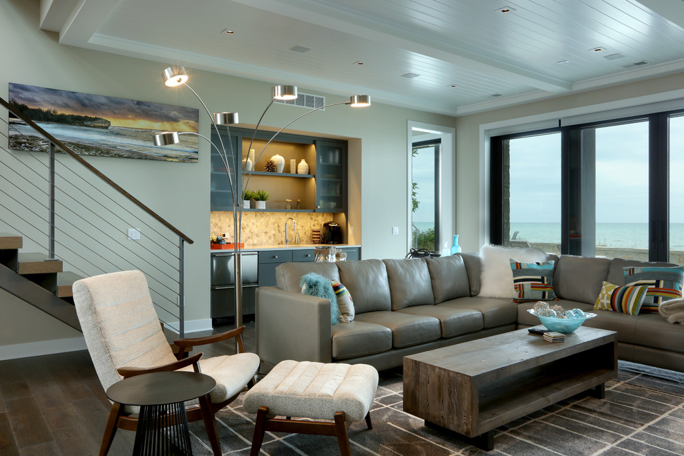 Imagen de sala de estar abierta contemporánea grande con paredes grises, suelo de madera oscura, pared multimedia y suelo marrón