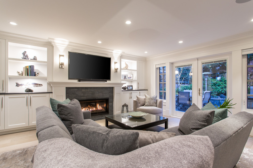 This is an example of a medium sized traditional open plan games room in Vancouver with a reading nook, grey walls, medium hardwood flooring, a standard fireplace, a tiled fireplace surround, a built-in media unit and beige floors.