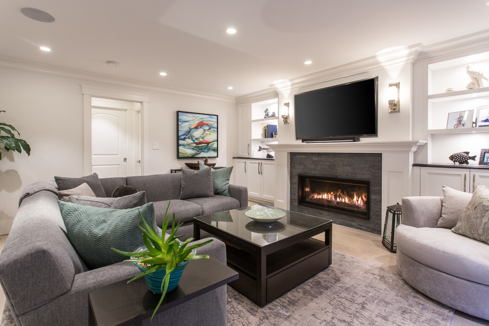 This is an example of a medium sized traditional open plan games room in Vancouver with a reading nook, grey walls, medium hardwood flooring, a standard fireplace, a tiled fireplace surround, a built-in media unit and beige floors.