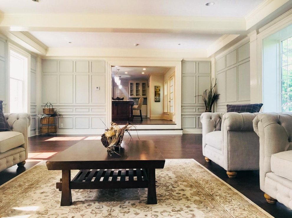 Example of a large classic open concept dark wood floor, exposed beam and wainscoting family room design in Cleveland with gray walls, a standard fireplace and a wood fireplace surround