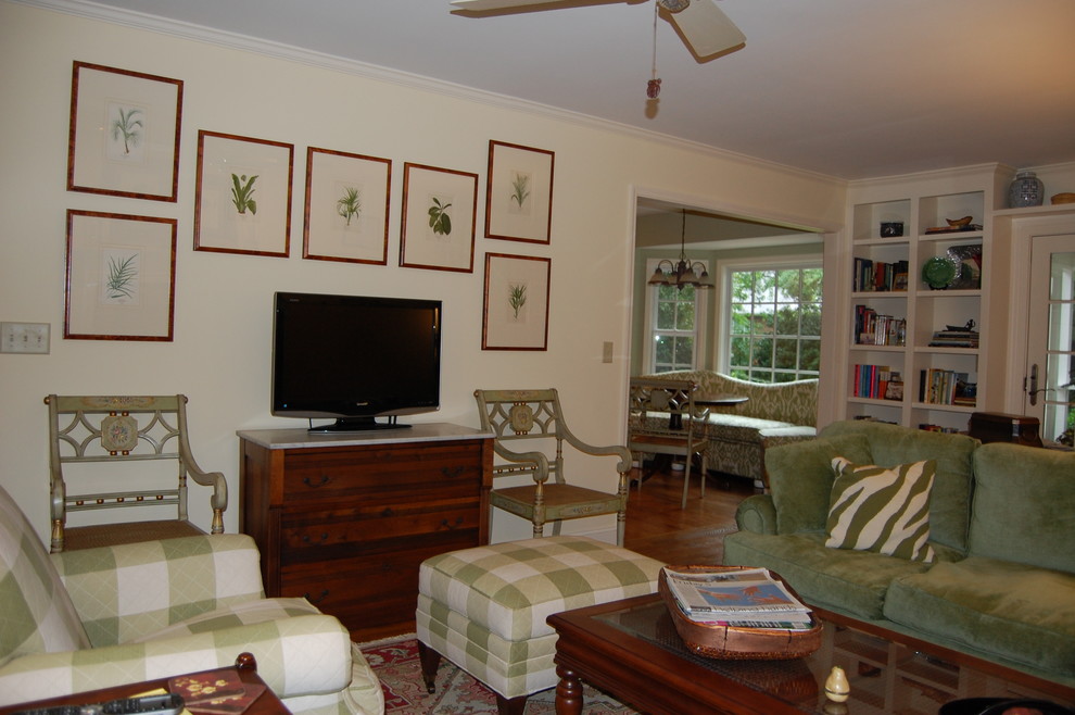 Mittelgroßes, Abgetrenntes Klassisches Wohnzimmer mit gelber Wandfarbe, braunem Holzboden, Kamin, Kaminumrandung aus Backstein, freistehendem TV und braunem Boden in Charleston