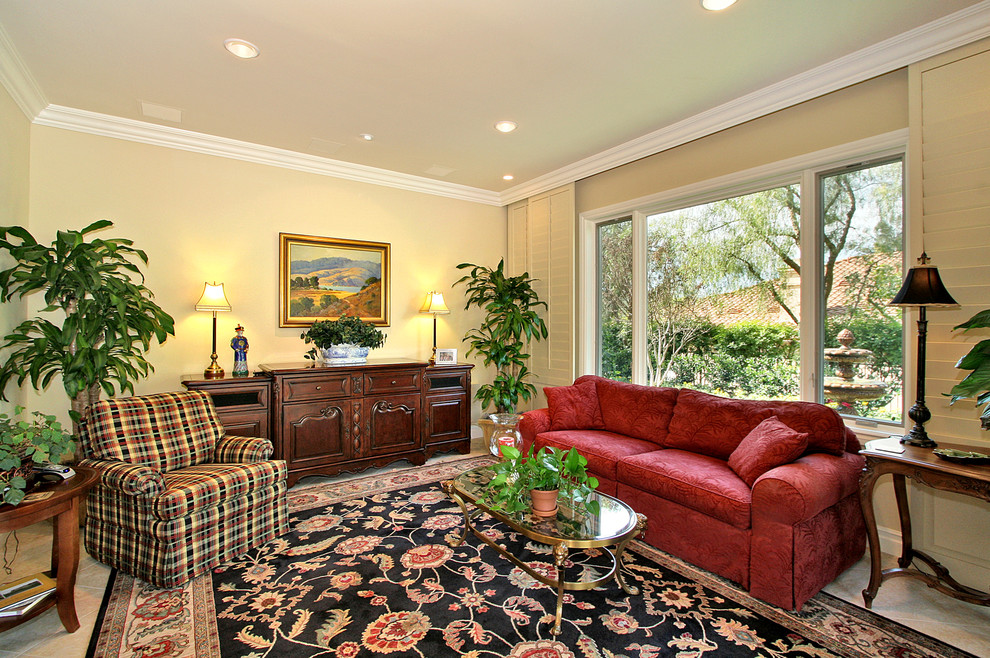 Foto de sala de estar abierta clásica de tamaño medio sin chimenea con paredes beige, suelo de mármol y televisor retractable