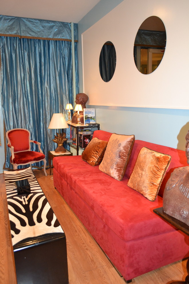 На фото: изолированная гостиная комната среднего размера в стиле фьюжн с синими стенами, паркетным полом среднего тона, стандартным камином, фасадом камина из дерева и коричневым полом