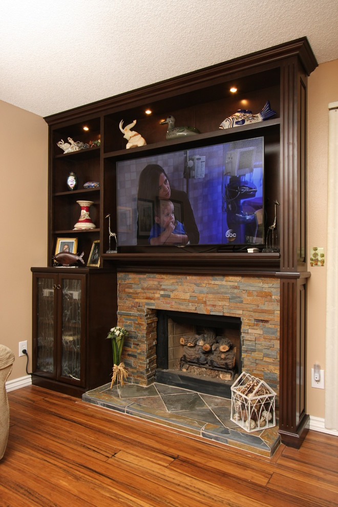 Kleiner, Offener Hobbyraum mit beiger Wandfarbe, braunem Holzboden, Kamin, TV-Wand und Kaminumrandung aus Stein in Orange County