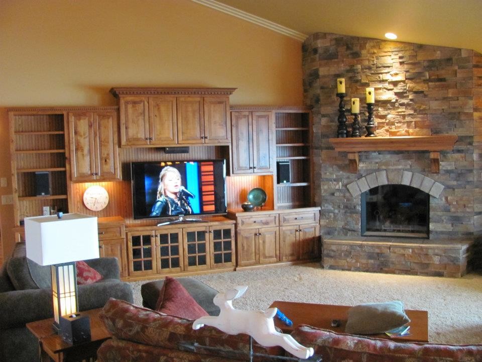 他の地域にある低価格の中くらいなラスティックスタイルのおしゃれなオープンリビング (ベージュの壁、カーペット敷き、暖炉なし、木材の暖炉まわり、壁掛け型テレビ) の写真