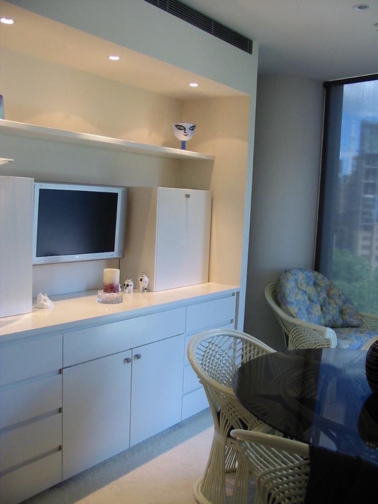 Immagine di un piccolo soggiorno moderno aperto con pareti bianche, moquette e TV a parete