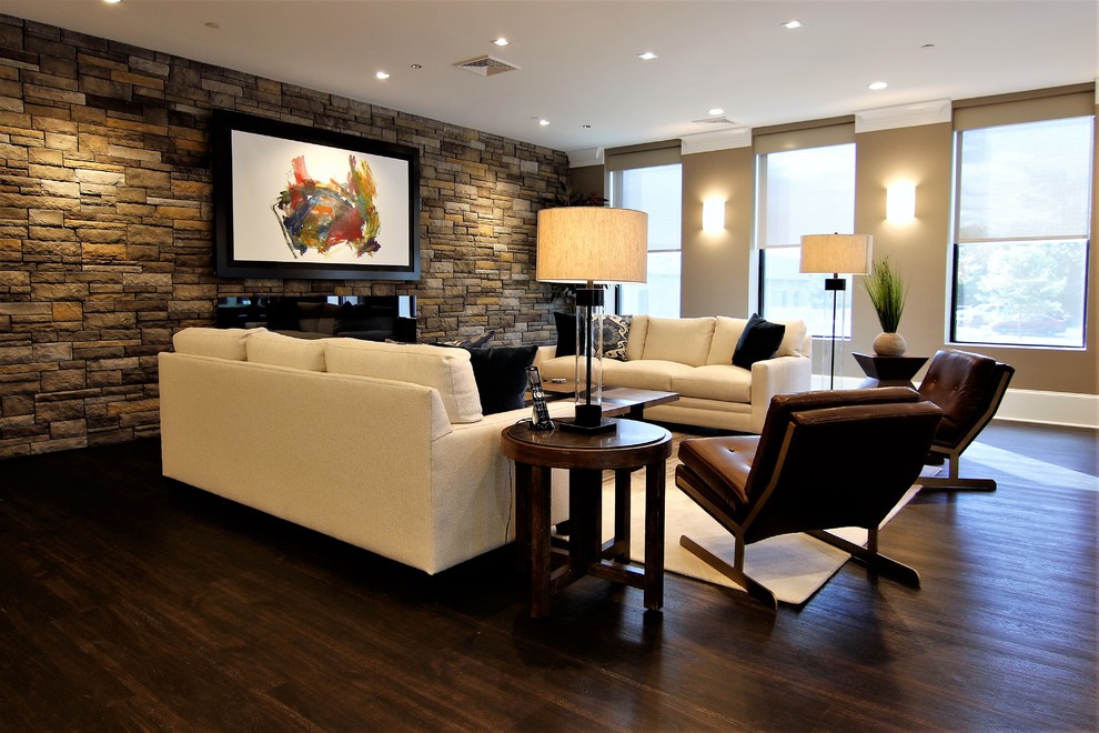Photo of a large modern open plan games room in Baltimore with beige walls, vinyl flooring, a hanging fireplace, a stone fireplace surround, a concealed tv and brown floors.