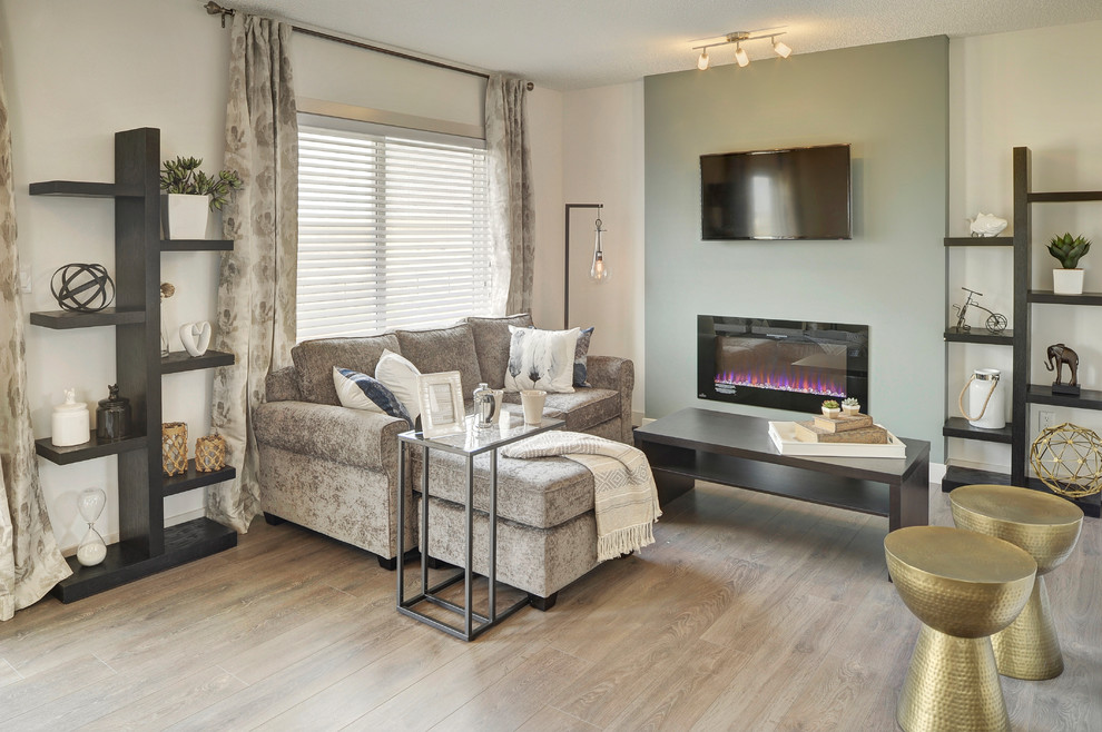 This is an example of a small traditional open plan games room in Edmonton with white walls, laminate floors, a hanging fireplace, a wall mounted tv and grey floors.