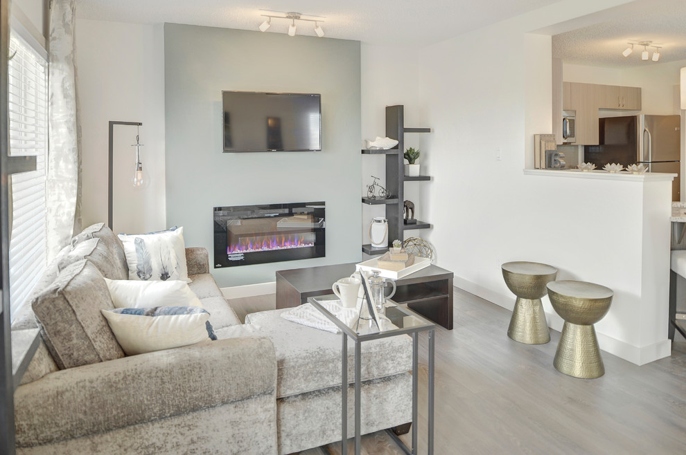 Diseño de sala de estar abierta clásica pequeña con paredes blancas, suelo laminado, chimeneas suspendidas, televisor colgado en la pared y suelo gris