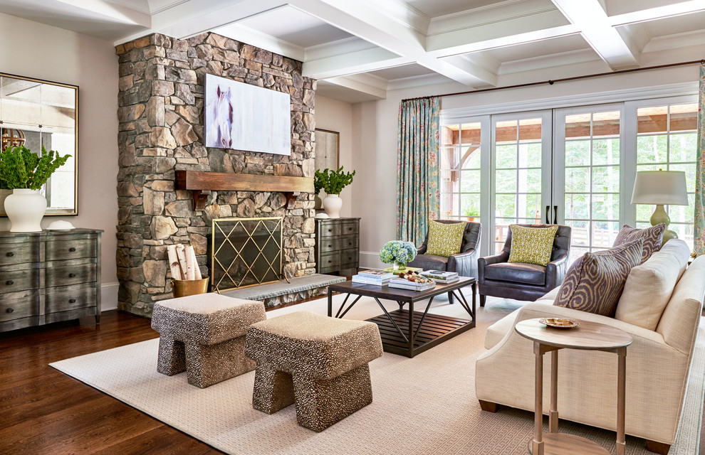 Landhaus Wohnzimmer mit beiger Wandfarbe, dunklem Holzboden, Kamin und Kaminumrandung aus Stein in Charlotte