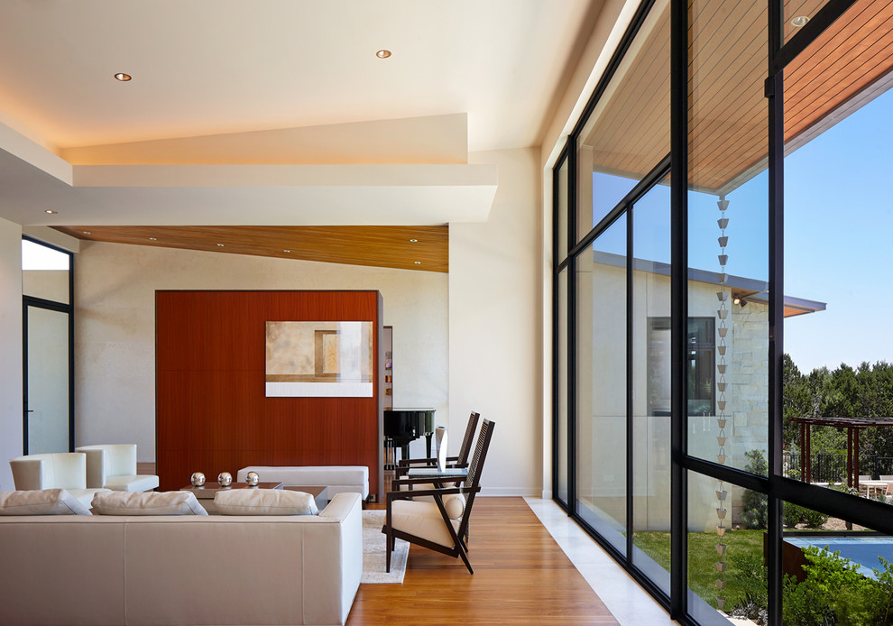 Idee per un soggiorno design aperto con pareti bianche, pavimento in legno massello medio e TV nascosta