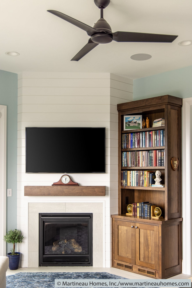 Свежая идея для дизайна: открытая гостиная комната среднего размера в стиле фьюжн с синими стенами, полом из керамогранита, стандартным камином, фасадом камина из вагонки, телевизором на стене и серым полом - отличное фото интерьера
