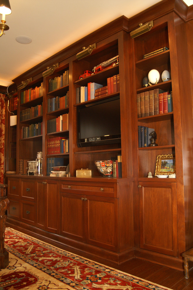 Cette photo montre une grande salle de séjour chic ouverte avec une bibliothèque ou un coin lecture, parquet foncé et un téléviseur encastré.