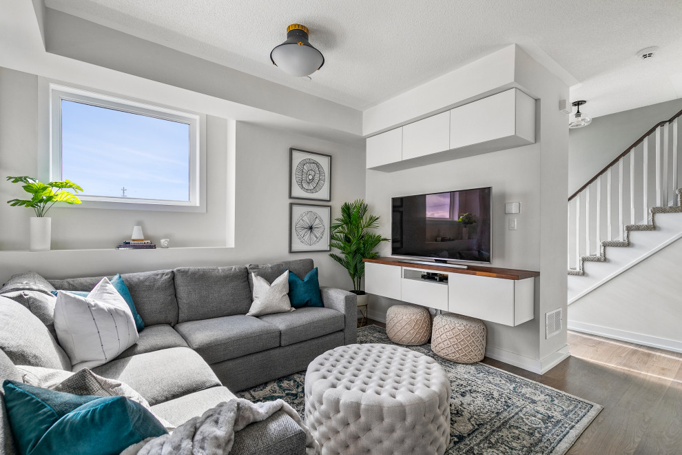 Klassisches Wohnzimmer mit grauer Wandfarbe, dunklem Holzboden, TV-Wand und braunem Boden in Toronto