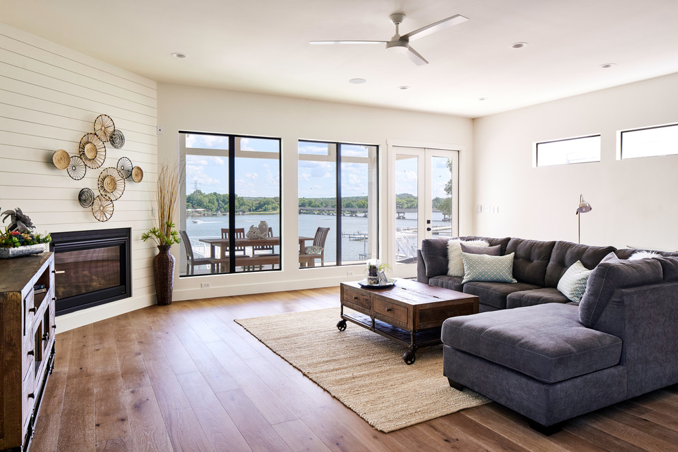 Maritimes Wohnzimmer mit weißer Wandfarbe, braunem Holzboden und Eckkamin in Sonstige