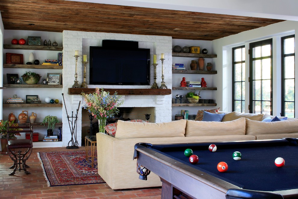 Imagen de sala de estar mediterránea con todas las chimeneas, marco de chimenea de ladrillo y alfombra