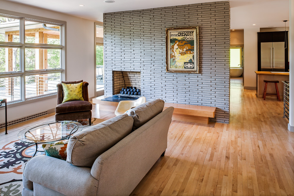 Immagine di un soggiorno design di medie dimensioni e chiuso con pareti beige, parquet chiaro, camino classico, nessuna TV e cornice del camino in mattoni