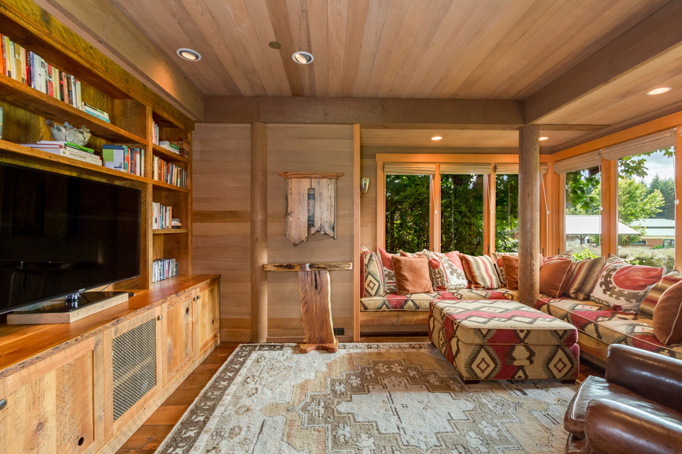 Family room library - huge rustic enclosed medium tone wood floor family room library idea in Seattle with a media wall
