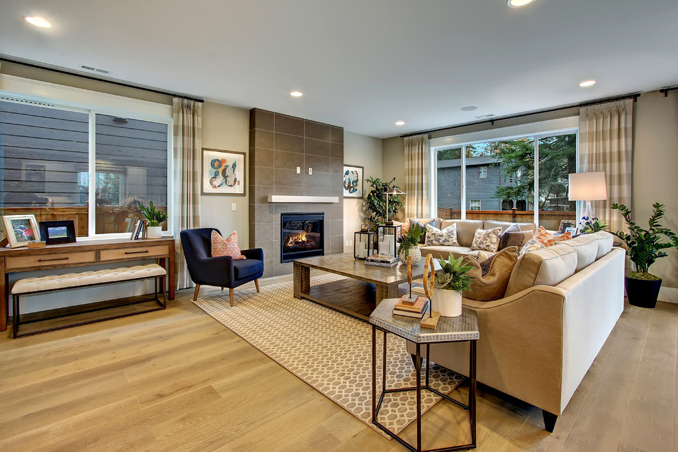 Family room - transitional open concept light wood floor family room idea in Seattle with beige walls, a standard fireplace, a tile fireplace and a wall-mounted tv