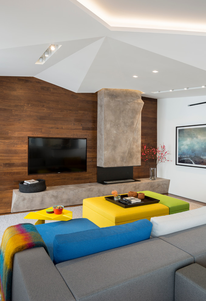Cette image montre une salle de séjour minimaliste de taille moyenne et fermée avec salle de jeu, un mur blanc, un sol en bois brun, une cheminée standard, un manteau de cheminée en béton et un téléviseur fixé au mur.