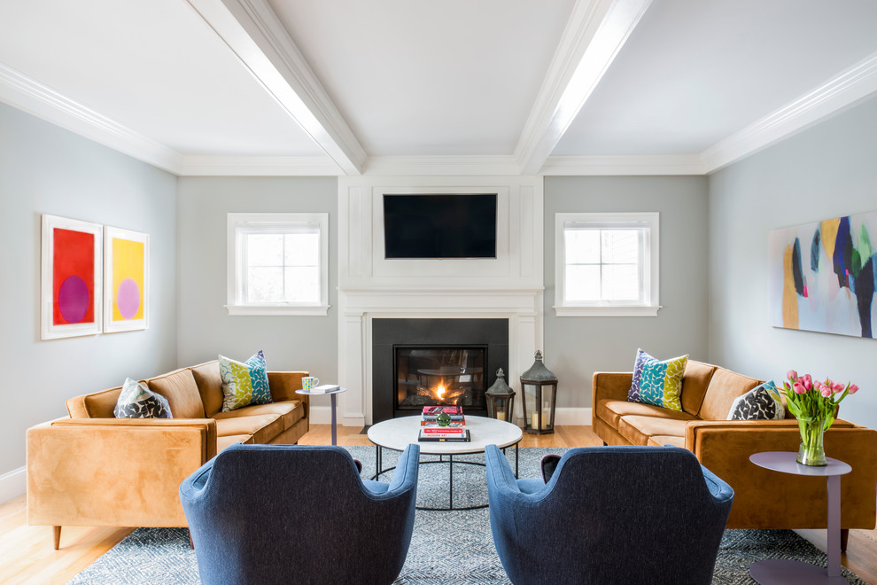 Пример оригинального дизайна: гостиная комната в стиле неоклассика (современная классика) с серыми стенами, светлым паркетным полом, стандартным камином и телевизором на стене