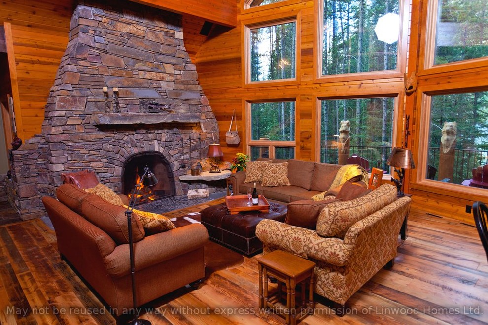 Inspiration pour une grande salle de séjour chalet ouverte avec un mur marron, un sol en bois brun, une cheminée standard, un manteau de cheminée en pierre et aucun téléviseur.