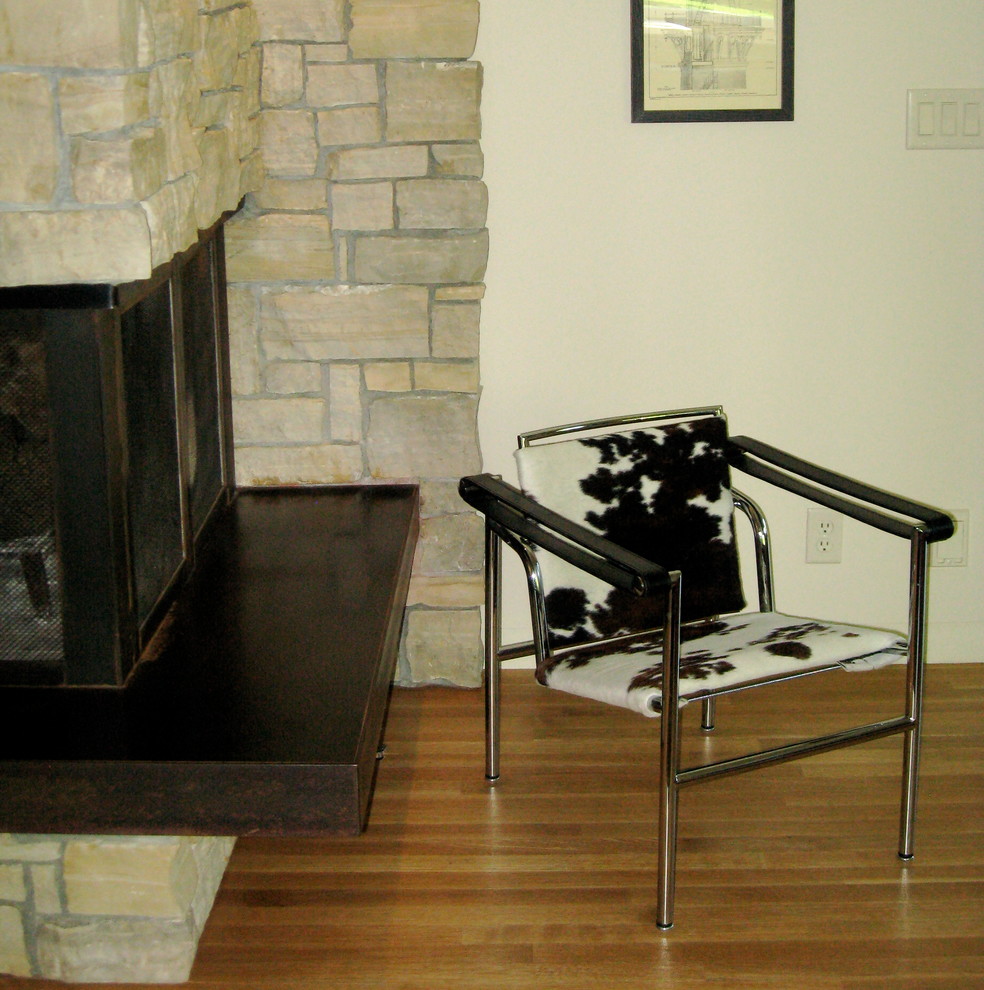 Modernes Wohnzimmer mit hellem Holzboden und Kaminumrandung aus Stein in Kansas City