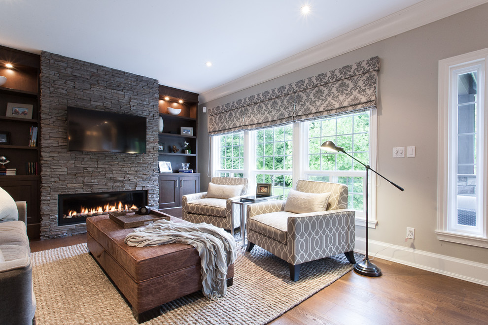 Großes, Abgetrenntes Klassisches Wohnzimmer mit grauer Wandfarbe, braunem Holzboden, Gaskamin, Kaminumrandung aus Stein und TV-Wand in Vancouver
