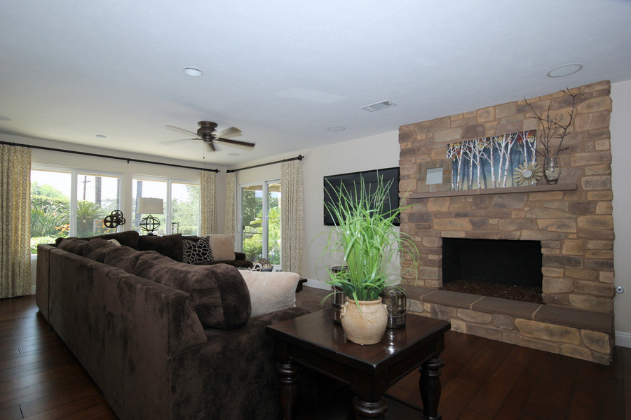 Mid-sized transitional open concept medium tone wood floor family room photo in Los Angeles with a bar, beige walls, a standard fireplace, a stone fireplace and a wall-mounted tv