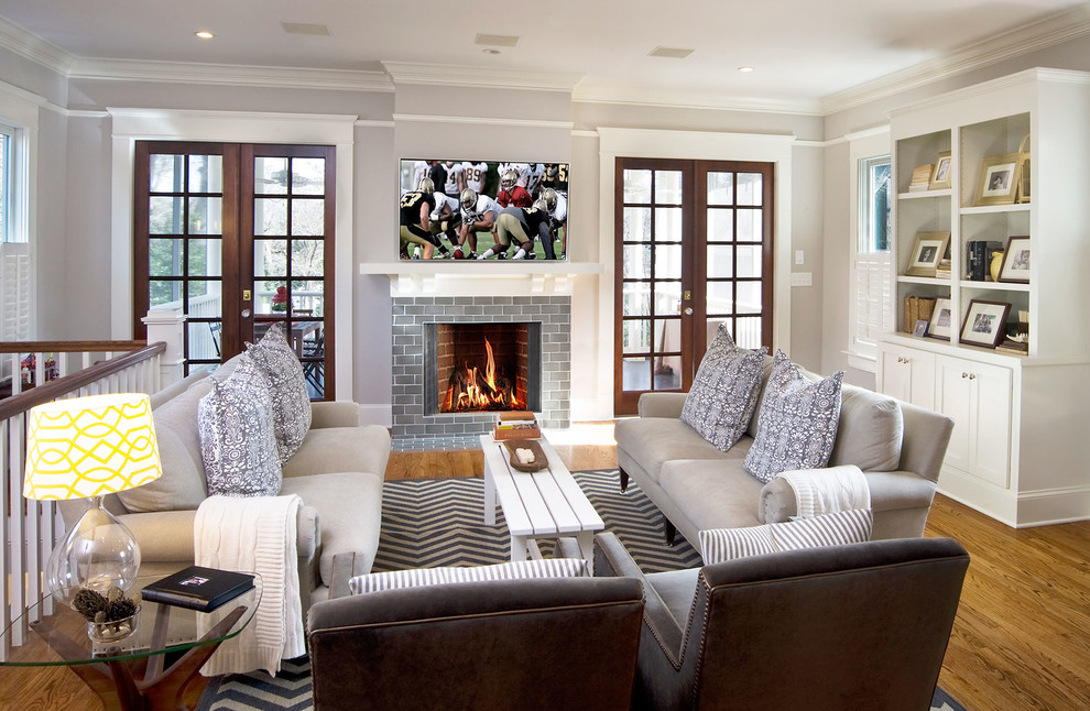 Ejemplo de sala de estar tradicional con paredes grises, suelo de madera en tonos medios, todas las chimeneas, televisor colgado en la pared, marco de chimenea de baldosas y/o azulejos y alfombra