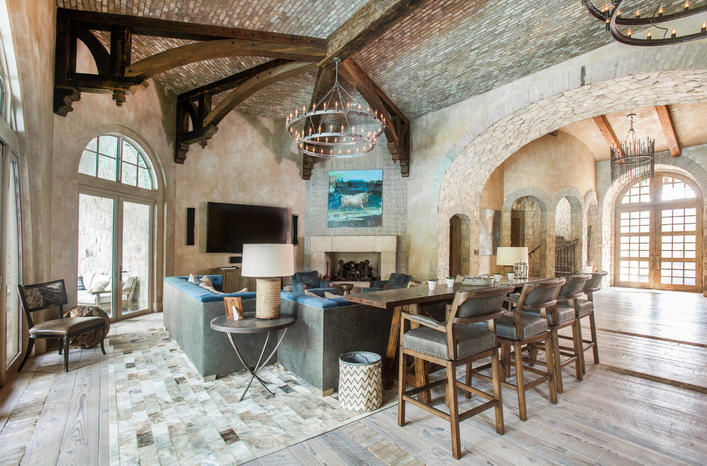 This is an example of an expansive traditional open plan games room in Houston with beige walls, medium hardwood flooring, a corner fireplace, a stone fireplace surround, a wall mounted tv and feature lighting.