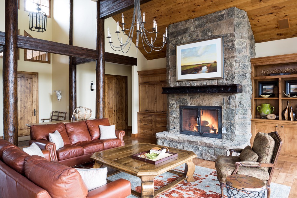 Example of a mountain style open concept medium tone wood floor family room design in Portland with beige walls, a standard fireplace, a stone fireplace and a concealed tv